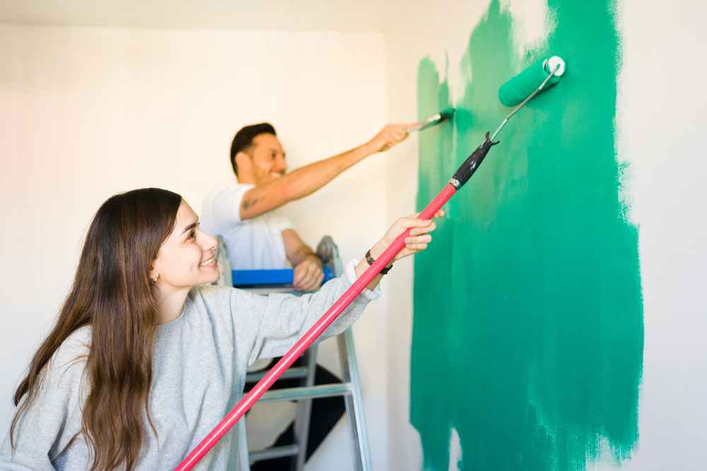 Thrilled,Young,Woman,And,Man,Painting,Happily,The,Walls,Of
